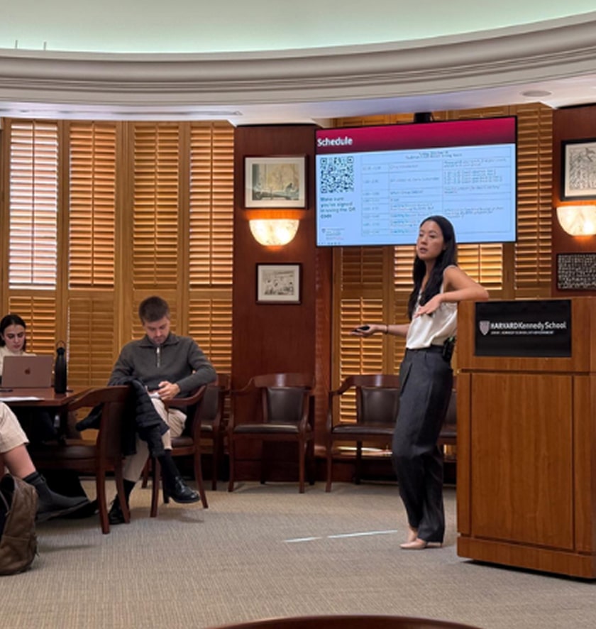 Students in a classroom face a presentation screen during a lecture run by Joan Moon.