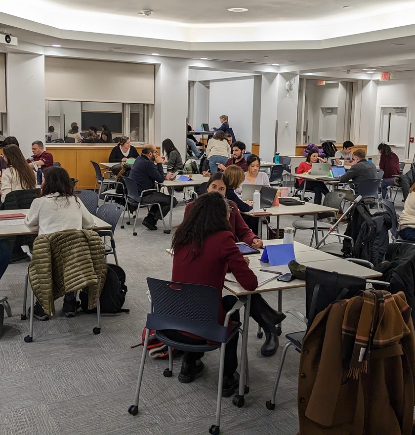 A classroom filled with multiple small working groups running negotiation simulations.