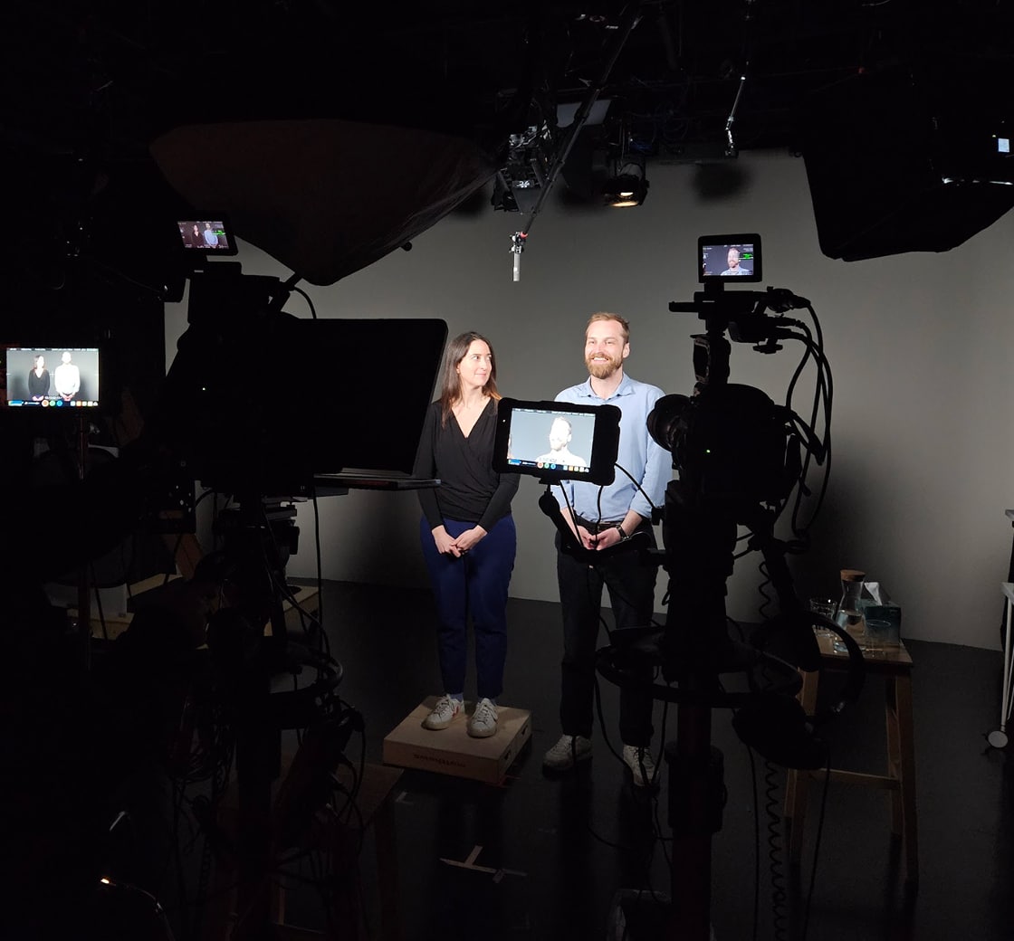 Monica Giannone and Anselm Dannecker being filmed on a studio set with camera and lighting.