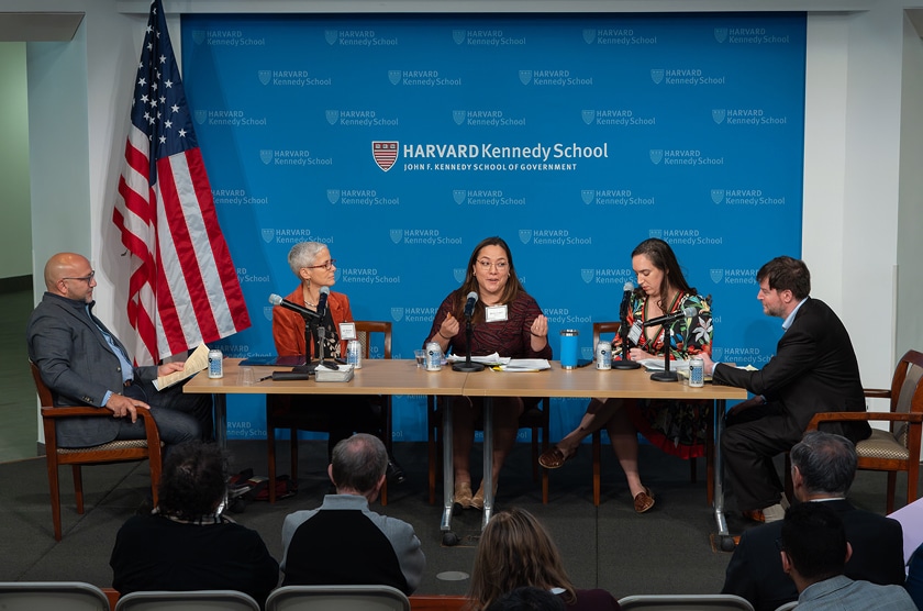 Four panelists speak on stage in front of a Harvard Kennedy School backdrop.